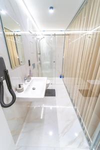 uma casa de banho branca com um lavatório e um chuveiro em Hotel Zemplín em Trebišov