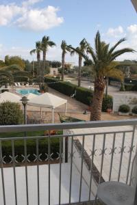 d'un balcon avec vue sur la piscine et les palmiers. dans l'établissement Masseria Casale Dei Fornici, à Polignano a Mare