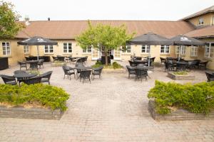 a courtyard with tables and chairs and umbrellas at Rønnes Hotel in Fjerritslev