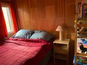 a bedroom with a bed with a red blanket and a lamp at Cozy mountain cottage with terrace in Dolni Lomna in Dolní Lomná