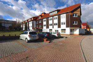 dois carros estacionados num parque de estacionamento em frente a um edifício em Carea Harz Hotel Allrode em Allrode