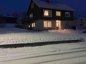 una casa en una calle cubierta de nieve por la noche en Strandveien 71, en Skjervøy