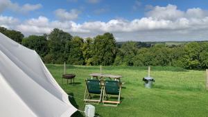 two chairs and a table in a field at Home Farm Radnage Glamping Bell Tent 4, with Log Burner and Fire Pit in Radnage