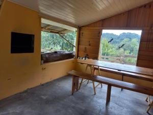 a room with a wooden table and a window at CASA DE CAMPO RIO CANOAS in Urubici