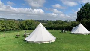 zwei weiße Zelte auf einem Grasfeld in der Unterkunft Home Farm Radnage Glamping Bell Tent 4, with Log Burner and Fire Pit in Radnage