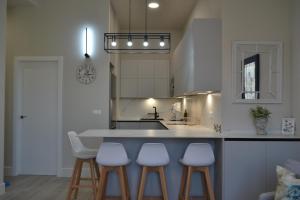 a kitchen with three bar stools and a kitchen island at SunShine Capricho de las Tendillas in Córdoba