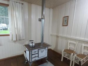 a stove in a room with two chairs and a window at CASA DE CAMPO RIO CANOAS in Urubici