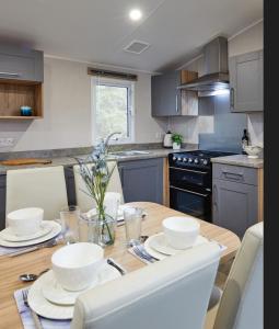 Beauview Brand New For 2023 Wi-Fi and Smart TV في ميلوم: مطبخ مع طاولة خشبية مع صحون بيضاء عليه
