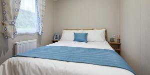 a bedroom with a blue and white bed with a window at Beauview Brand New For 2023 Wi-Fi and Smart TV in Millom