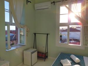 a bedroom with two windows and a bed with towels at Eolos House Cunda in Ayvalık