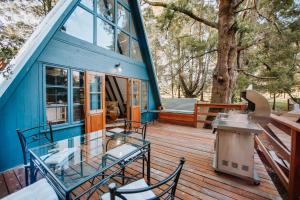 Hide Away Cabin في كنيسنا: منزل ازرق بطاولة زجاجية وكراسي على سطح