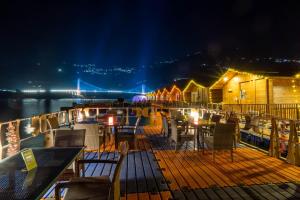 a deck with chairs and tables on a boat at night at Le ROI Floating Huts & Eco Rooms Tehri in Tehri-Garhwāl