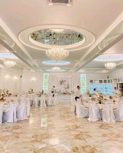 un salón de banquetes con mesas blancas y sillas blancas en Hotel and Restaurant Velure, en Mukácheve