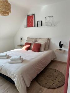 1 dormitorio con 1 cama blanca grande con almohadas rojas en Maison Ker Ria, en Locoal-Mendon
