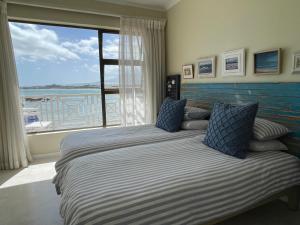 a bedroom with two beds and a large window at By Die See in Gordonʼs Bay