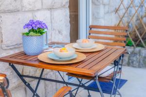 a wooden table with two bowls and a vase of flowers at Apartments Galatea with garage parking in Opatija