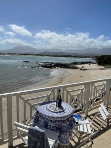 a bottle of wine sitting on a table on the beach at By Die See in Gordonʼs Bay