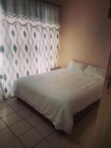 1 dormitorio con cama blanca y ventana en Stay Inn Krugersdorp en Krugersdorp