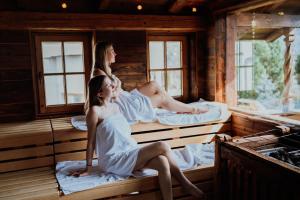 Due donne sedute sui letti in una sauna di Sport- und Wellnesshotel Held 4 Sterne Superior a Fügen