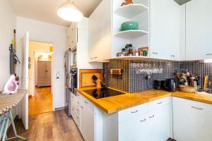 una cucina con armadietti bianchi e ripiani in legno di GuestReady - Calm retreat in vibrant Belleville a Parigi