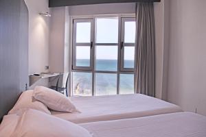 a bedroom with a bed and a window with the ocean at Hotel Chiqui in Santander