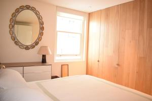 a bedroom with a white bed and a mirror at Beautiful Kensington flat in London