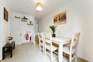 a white dining room with a white table and chairs at Wesferry beds to stay in London