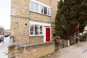 ein Backsteinhaus mit einer roten Tür auf einer Straße in der Unterkunft Wesferry beds to stay in London