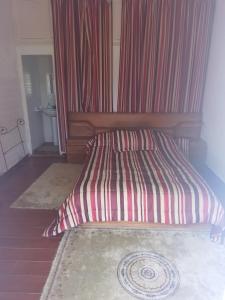 - un lit avec un oreiller rayé dans l'établissement Firma lfassiya, à Dar SaÃ¯d Ben Hajj