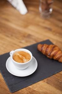 a cup of coffee and a croissant on a black napkin at Mesón Kubano B&B in Sant Mateu