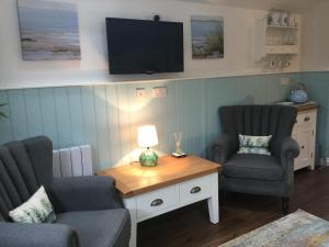 un soggiorno con 2 sedie e un tavolo con una TV di Angel Cottage a Drymen