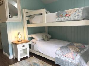 a bedroom with two bunk beds and a table with a lamp at Angel Cottage in Drymen