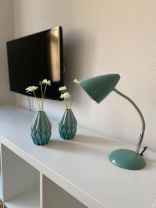 a desk with two vases and a lamp on it at Gemütliche Wohnung Nähe Rhein in Basel