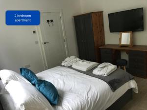 a bedroom with a bed with blue pillows and a television at Ocean View Apartments in Looe