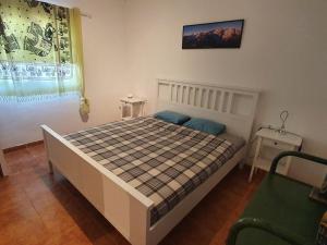 a bedroom with a bed with a checkered blanket and a window at Finca la fortaleza in San Miguel de Abona