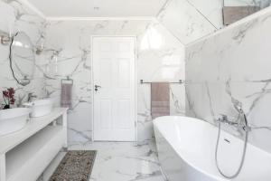 a bathroom with white marble walls and a tub and sink at 3 Bedroom Hilltop Home with Spectacular Views in Cape Town