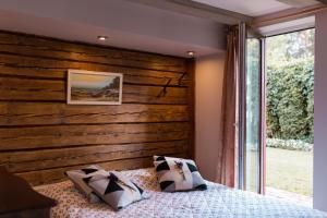um quarto com uma parede de madeira e uma cama com almofadas em Miera osta atpūtai Skultē Garāža em Skulte