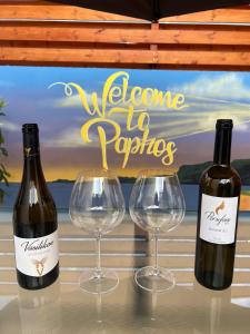 Three Bedroom Casa de Paphos في بافوس: زجاجتان من النبيذ وكأسين على طاولة