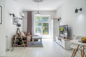 a white living room with a couch and a tv at Jazz & Wine - Luxury apARTment By The Sea & Parking & HBO & Netflix in Varna City