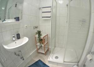 a white bathroom with a shower and a sink at Wiking App 19 in Grömitz