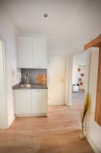 a kitchen with white cabinets and a wooden floor at Apartmenthaus Fritz Reuter in Schwerin