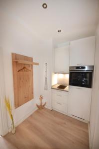 a kitchen with white cabinets and a wooden floor at Apartmenthaus Fritz Reuter in Schwerin