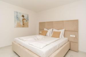 un grande letto bianco in una stanza con un dipinto di Apartmani Šimi - The Sun a Crikvenica