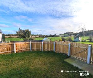 a wooden fence in a yard with a field behind it at The Paddock in Killyleagh