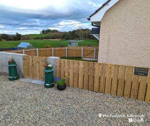 uma cerca de madeira com duas latas de lixo e plantas verdes em The Paddock em Killyleagh