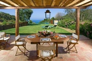 een houten tafel en stoelen op een patio bij La casa nella Macchia in Monte Argentario