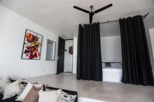 a living room with black curtains and a ceiling fan at Bieshu Beach Hive in Habaraduwa