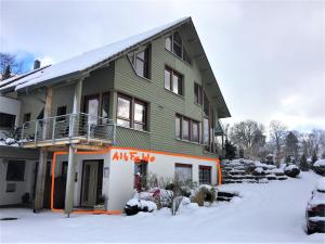 ein grünes Haus mit orangefarbenem Schnitt im Schnee in der Unterkunft Alb Fe Wo in Sankt Johann