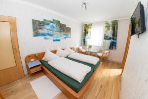 1 dormitorio con cama con almohadas blancas y mesa en Gästehaus-Pension Familie Dwars, en Spitz