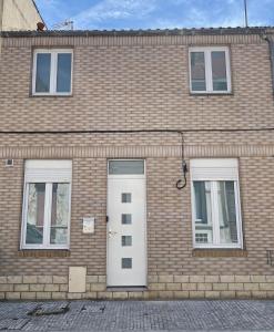 ein Backsteingebäude mit einer weißen Tür und zwei Fenstern in der Unterkunft Maison CALAIS centre ville L in Calais